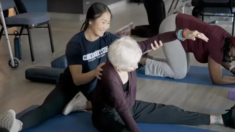 Therapist helping patient on floor mat with their arm movement.